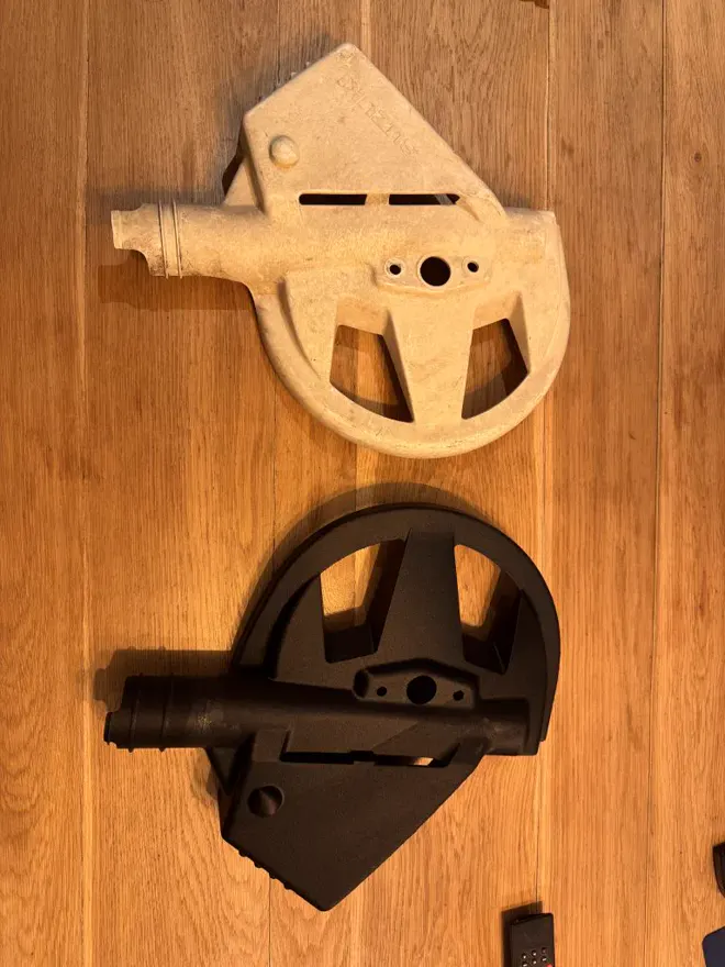 Une pièce d'origine claire, cassée, posée sur une table en bois au-dessus de sa copie noire imprimée en 3D